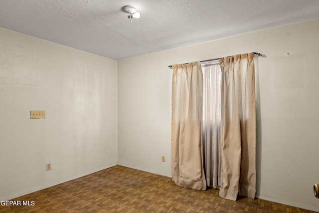 empty room with parquet flooring and a textured ceiling