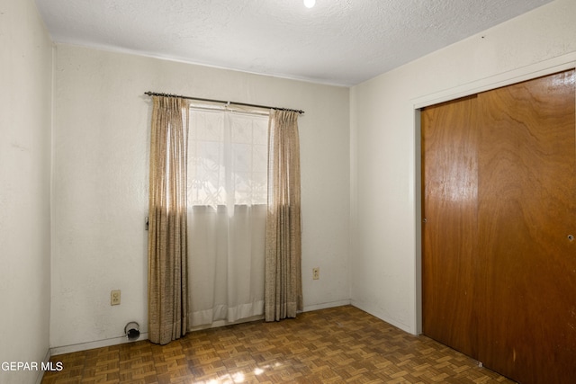 empty room with dark parquet flooring and a textured ceiling