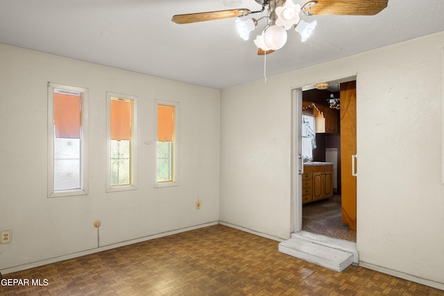 spare room featuring ceiling fan and dark parquet flooring