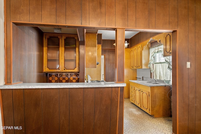 kitchen with sink, backsplash, kitchen peninsula, and wood walls