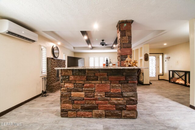 bar featuring an AC wall unit, ceiling fan, and a textured ceiling