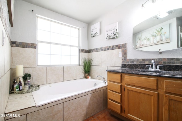 bathroom featuring tile patterned floors, tiled bath, and vanity