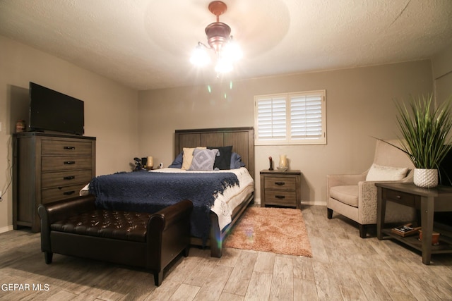 bedroom featuring a textured ceiling, ceiling fan, and light wood-type flooring