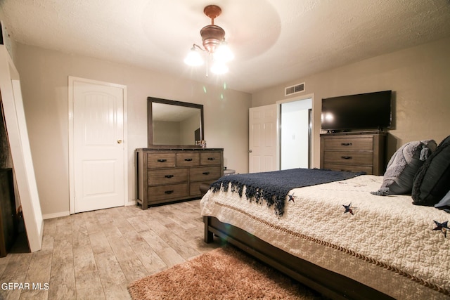 bedroom with a textured ceiling, ceiling fan, and light hardwood / wood-style floors