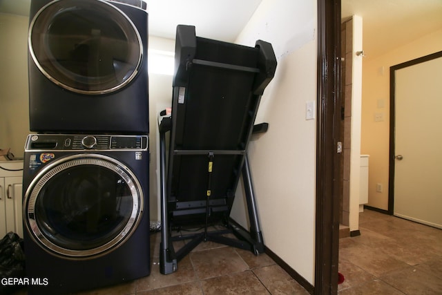 clothes washing area with dark tile patterned floors and stacked washer / drying machine