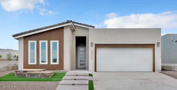 view of front of property with driveway, an attached garage, and stucco siding