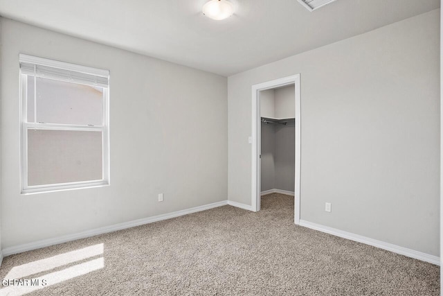 unfurnished bedroom with carpet flooring, a spacious closet, and a closet