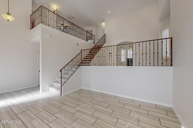 stairway featuring light tile patterned flooring and a towering ceiling