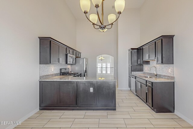 kitchen with sink, appliances with stainless steel finishes, tasteful backsplash, and high vaulted ceiling