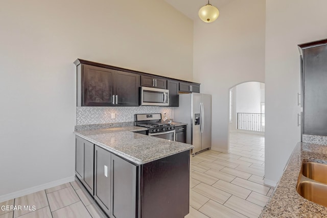 kitchen with light tile patterned flooring, stainless steel appliances, decorative backsplash, high vaulted ceiling, and light stone countertops