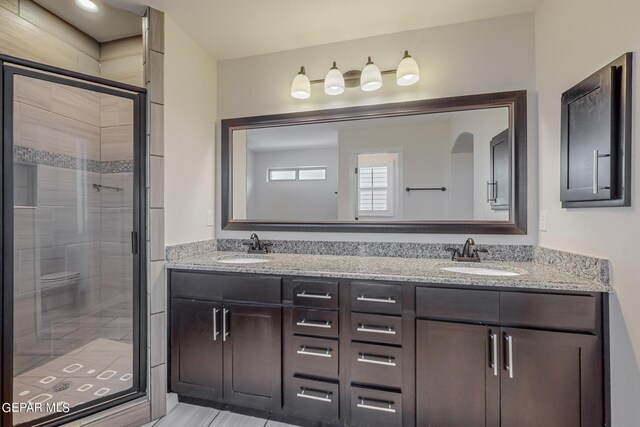 bathroom with a shower with door and double vanity