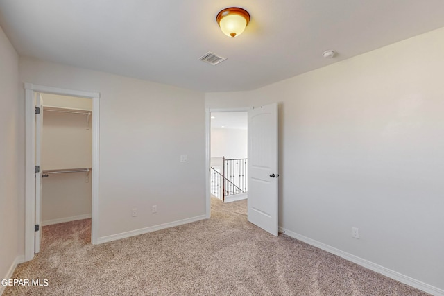 unfurnished bedroom with light colored carpet, a closet, and a spacious closet