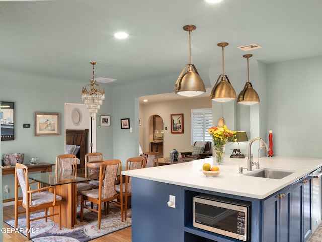 kitchen featuring a center island with sink, pendant lighting, blue cabinetry, and sink