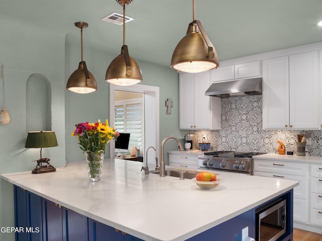 kitchen featuring hanging light fixtures, light stone countertops, white cabinetry, and range