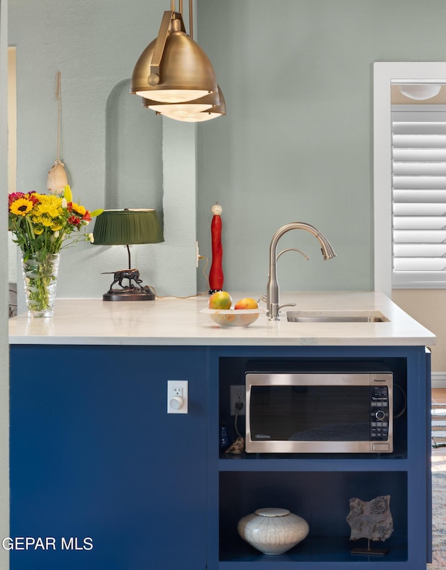 kitchen with sink, pendant lighting, and blue cabinets