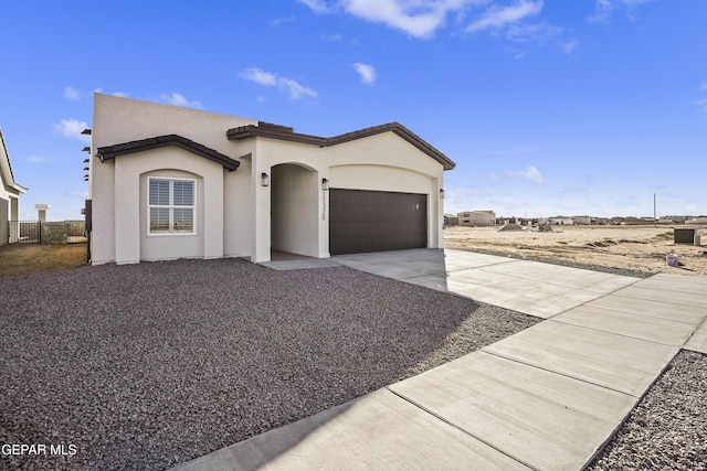 view of front of property featuring concrete driveway, an attached garage, and stucco siding