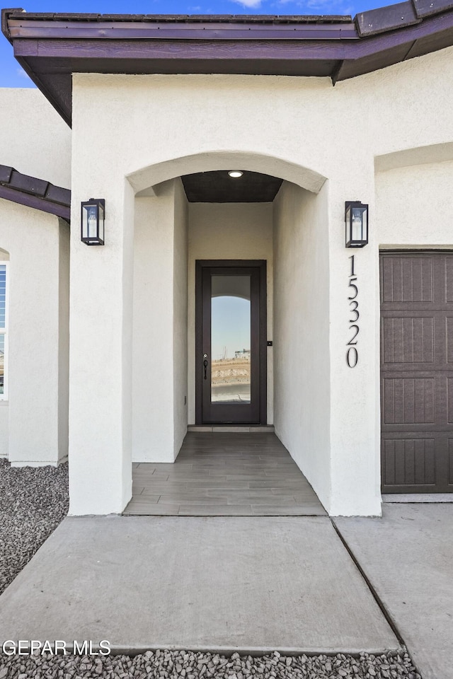 property entrance with a garage and stucco siding