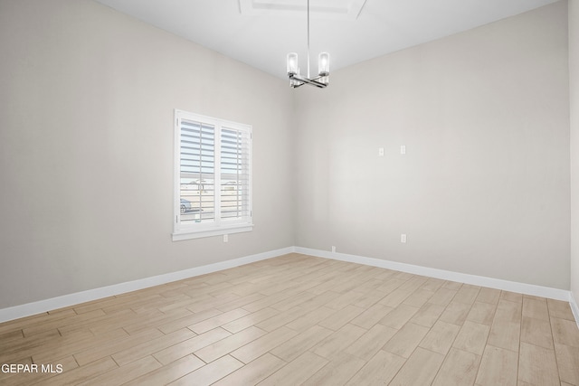 spare room featuring light wood-type flooring and an inviting chandelier