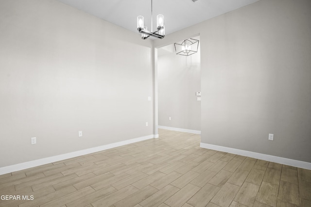 empty room featuring baseboards, an inviting chandelier, and light wood-type flooring