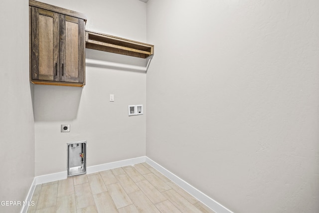 clothes washing area featuring cabinets, light hardwood / wood-style floors, hookup for a washing machine, and electric dryer hookup