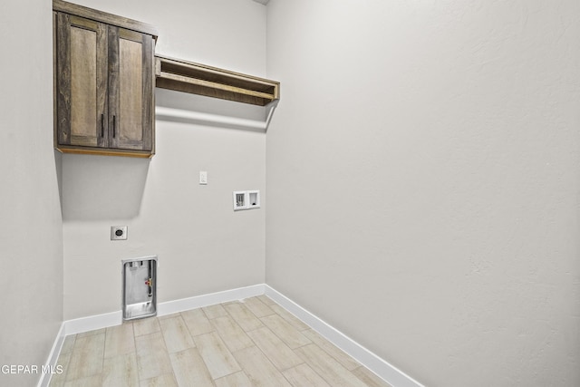 washroom with baseboards, light wood-type flooring, cabinet space, electric dryer hookup, and washer hookup