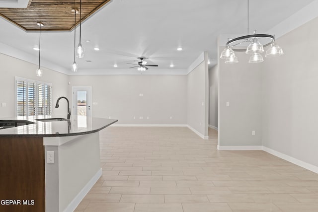 kitchen featuring pendant lighting, ceiling fan with notable chandelier, sink, and dark stone countertops