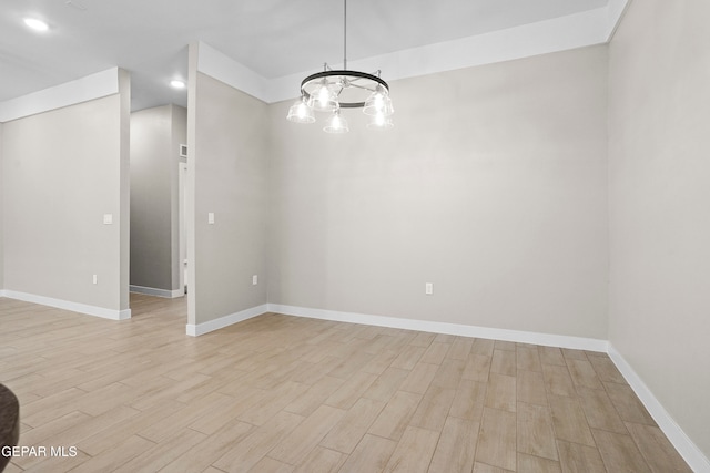 unfurnished room featuring a chandelier and light hardwood / wood-style flooring