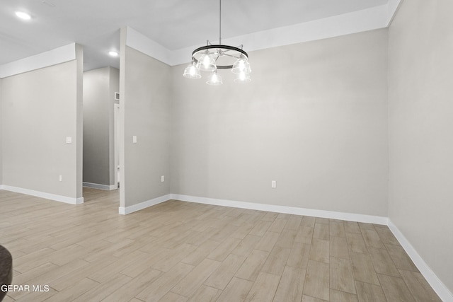 unfurnished room featuring an inviting chandelier, baseboards, and light wood-style flooring