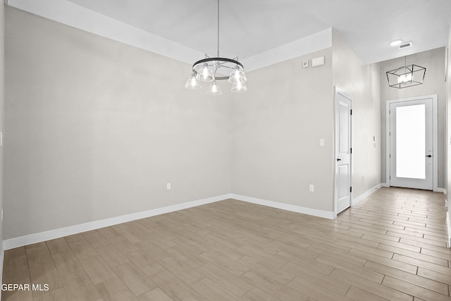 unfurnished dining area with baseboards, a chandelier, wood finished floors, and visible vents