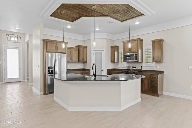 kitchen with hanging light fixtures, sink, a kitchen island with sink, and appliances with stainless steel finishes