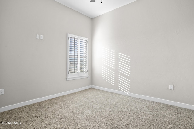 carpeted spare room featuring a ceiling fan and baseboards
