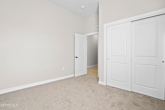 unfurnished bedroom with light colored carpet and a closet