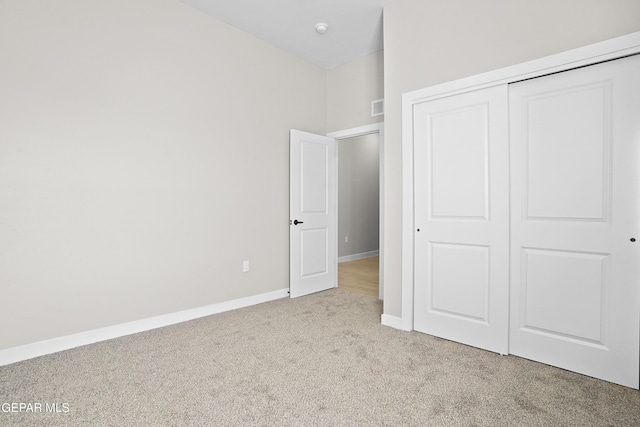 unfurnished bedroom with baseboards, carpet, a closet, and visible vents