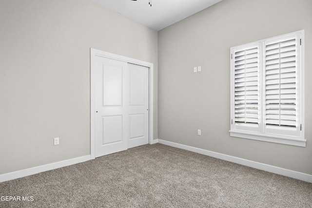 unfurnished bedroom with carpet floors, baseboards, and a closet