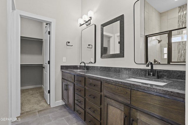 full bath featuring double vanity, a sink, a walk in closet, and a tile shower