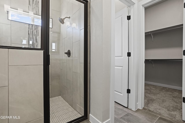 bathroom featuring baseboards, a stall shower, and a walk in closet