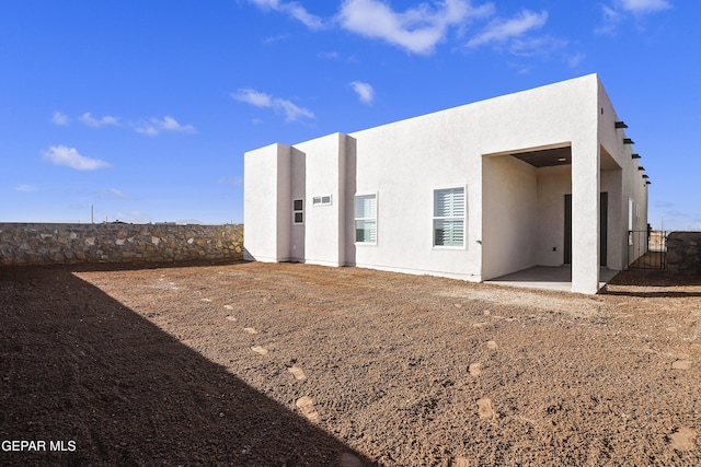 rear view of property with stucco siding and a patio area