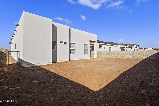 back of house featuring stucco siding and fence
