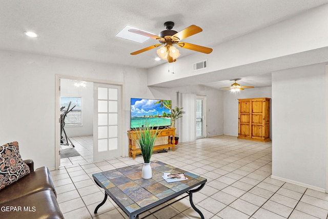 living room with light tile patterned floors, a textured ceiling, and ceiling fan