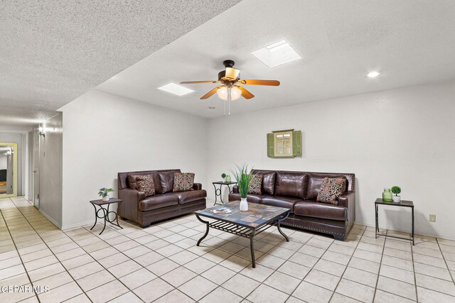 living room with a skylight, light tile patterned floors, a textured ceiling, and ceiling fan