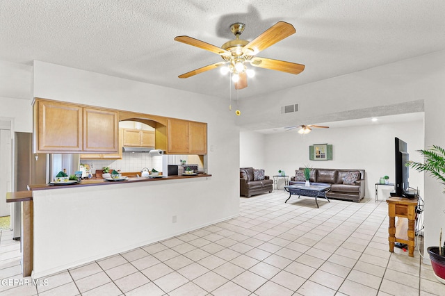 kitchen with a textured ceiling, ceiling fan, tasteful backsplash, and light tile patterned floors