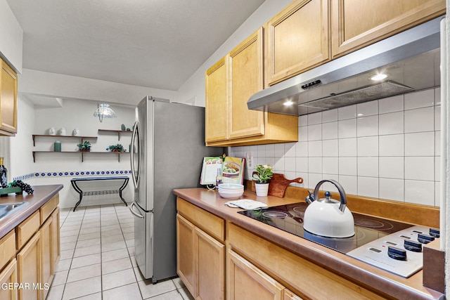 kitchen with tasteful backsplash, electric cooktop, stainless steel refrigerator, light tile patterned floors, and light brown cabinetry