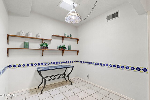 interior space featuring a textured ceiling, a skylight, and light tile patterned floors