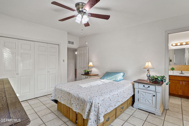 bedroom featuring light tile patterned floors, ceiling fan, ensuite bathroom, a closet, and sink