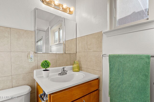 bathroom featuring vanity, toilet, and tile walls