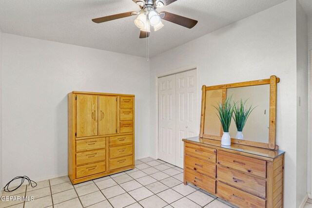 bedroom with a closet, a textured ceiling, light tile patterned floors, and ceiling fan