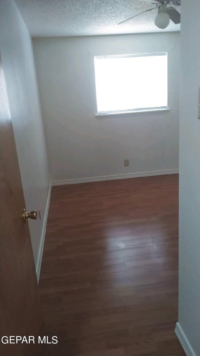 unfurnished room with a textured ceiling, wood finished floors, and a healthy amount of sunlight