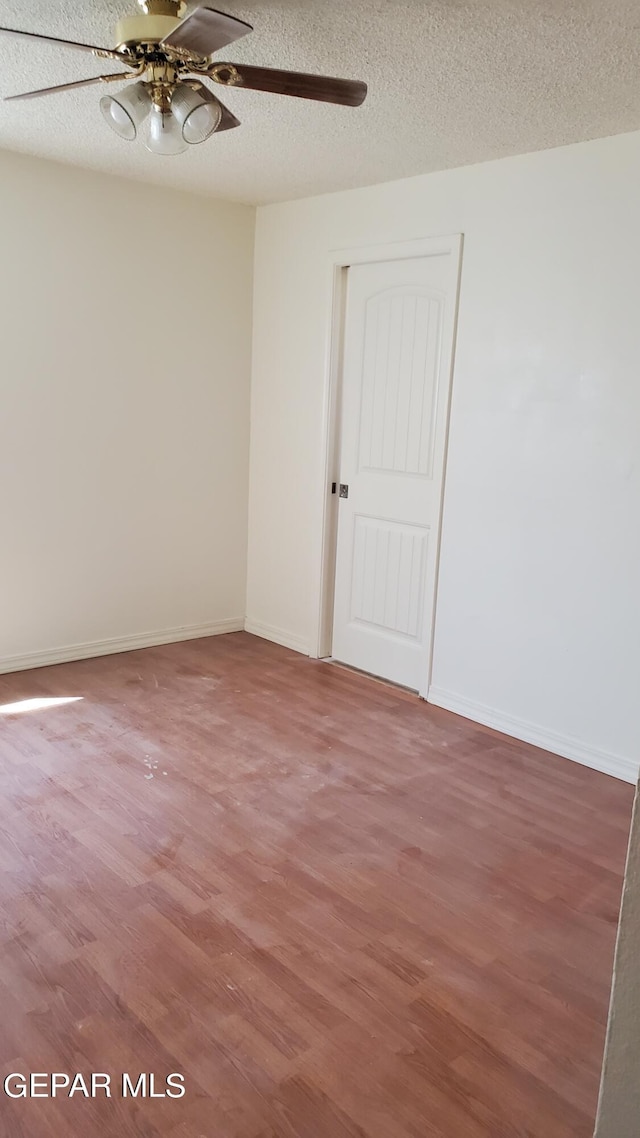 unfurnished room featuring baseboards, light wood-style flooring, a ceiling fan, and a textured ceiling