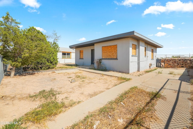 view of front of home featuring a patio area, fence, and stucco siding