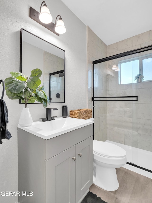 bathroom featuring vanity, hardwood / wood-style floors, toilet, and a shower with door